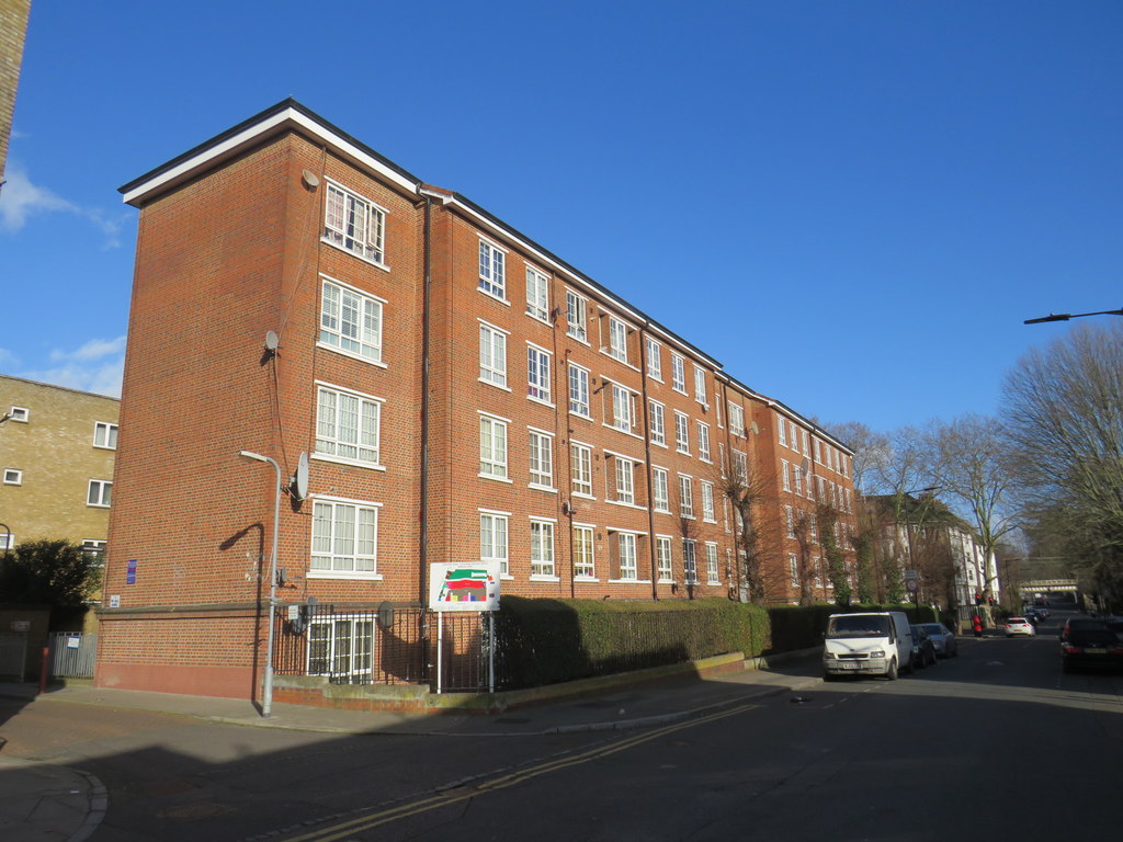 A row of red-brick housing association flats beside a street in Hackney.
