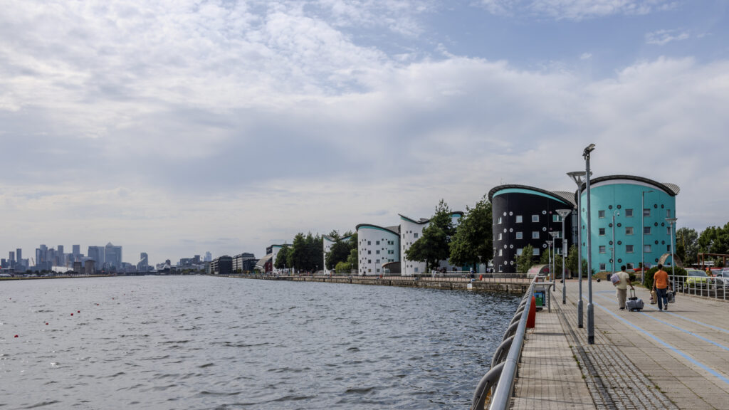 Campus buildings and a waterside path beside Royal Albert Dock.
